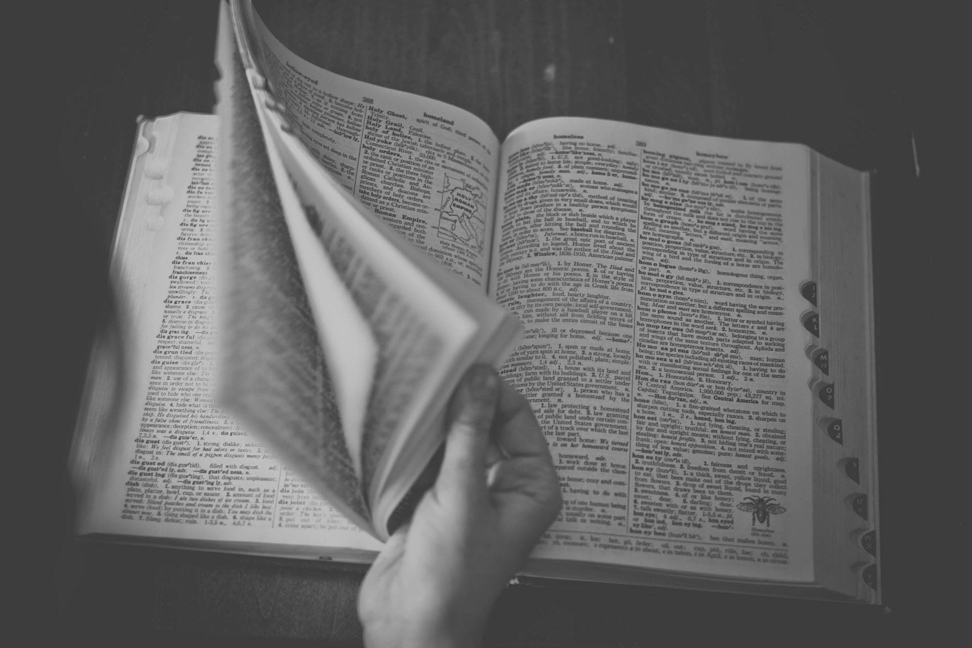 A hand turning the page of an open policy binder on a quiet desk.